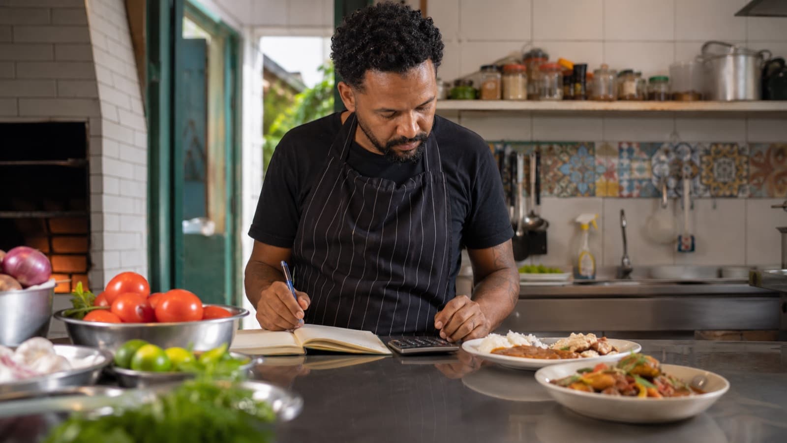 Dono de restaurante anotando os custos dos pratos na cozinha
