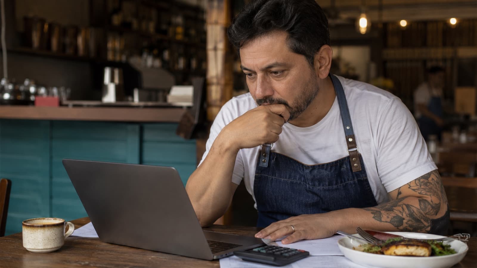 Dono de restaurante preocupado analisando as contas no laptop