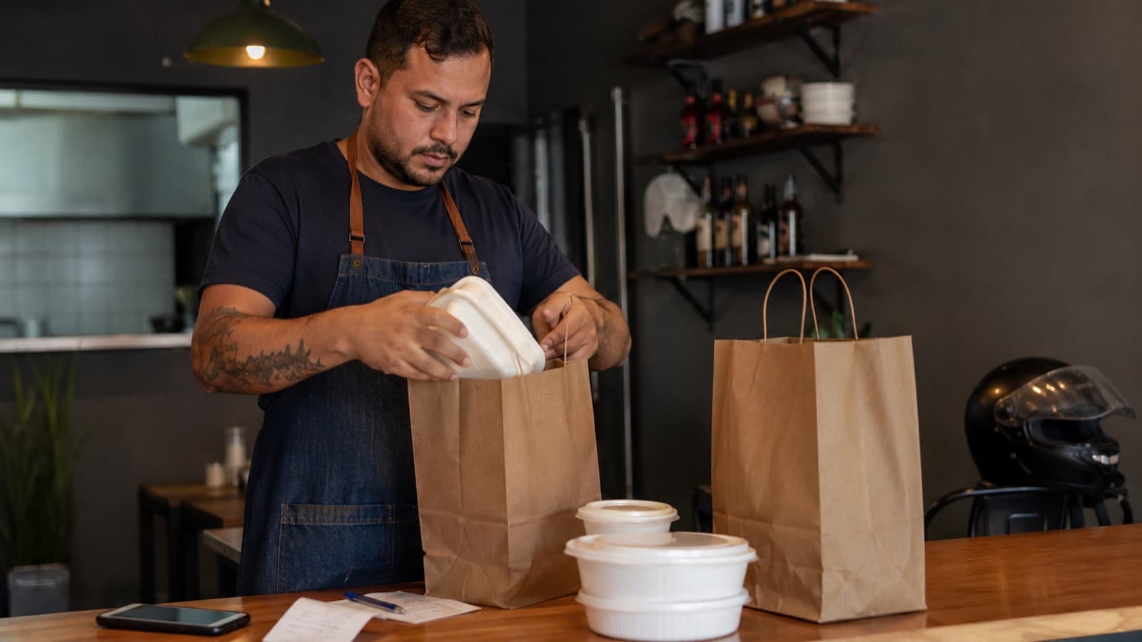 Dono de restaurante embalando pedido de delivery