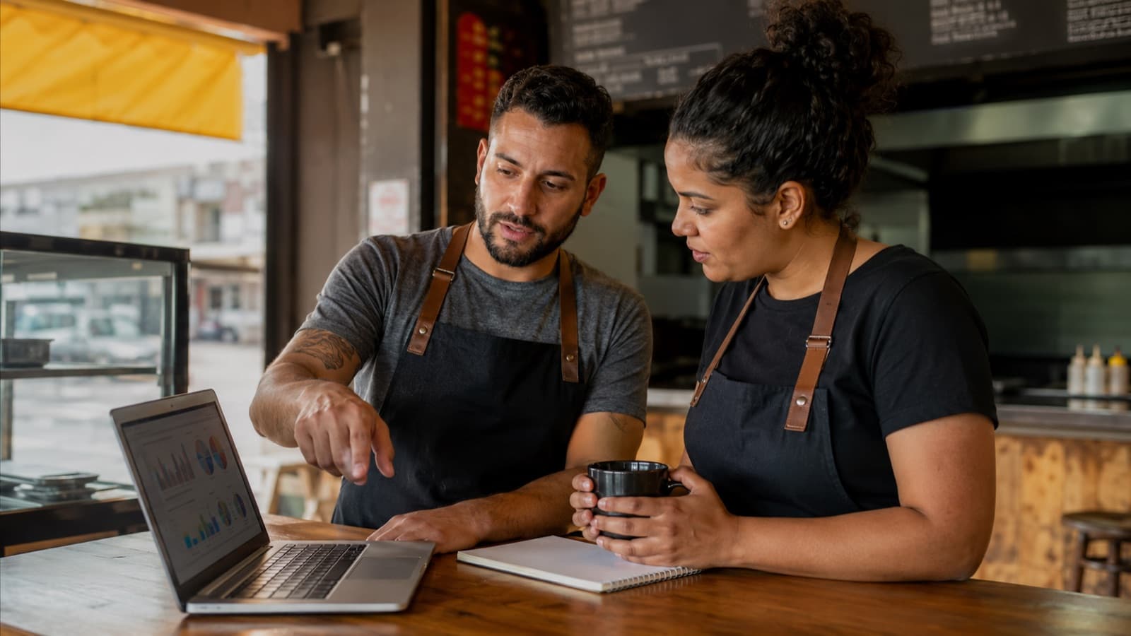 Sócios de restaurante revisando as contas do mês no notebook
